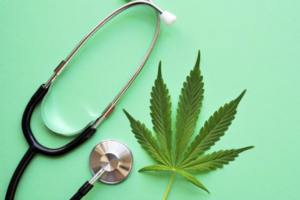 лист марихуаны и стетоскоп на светло-зелёном фоне